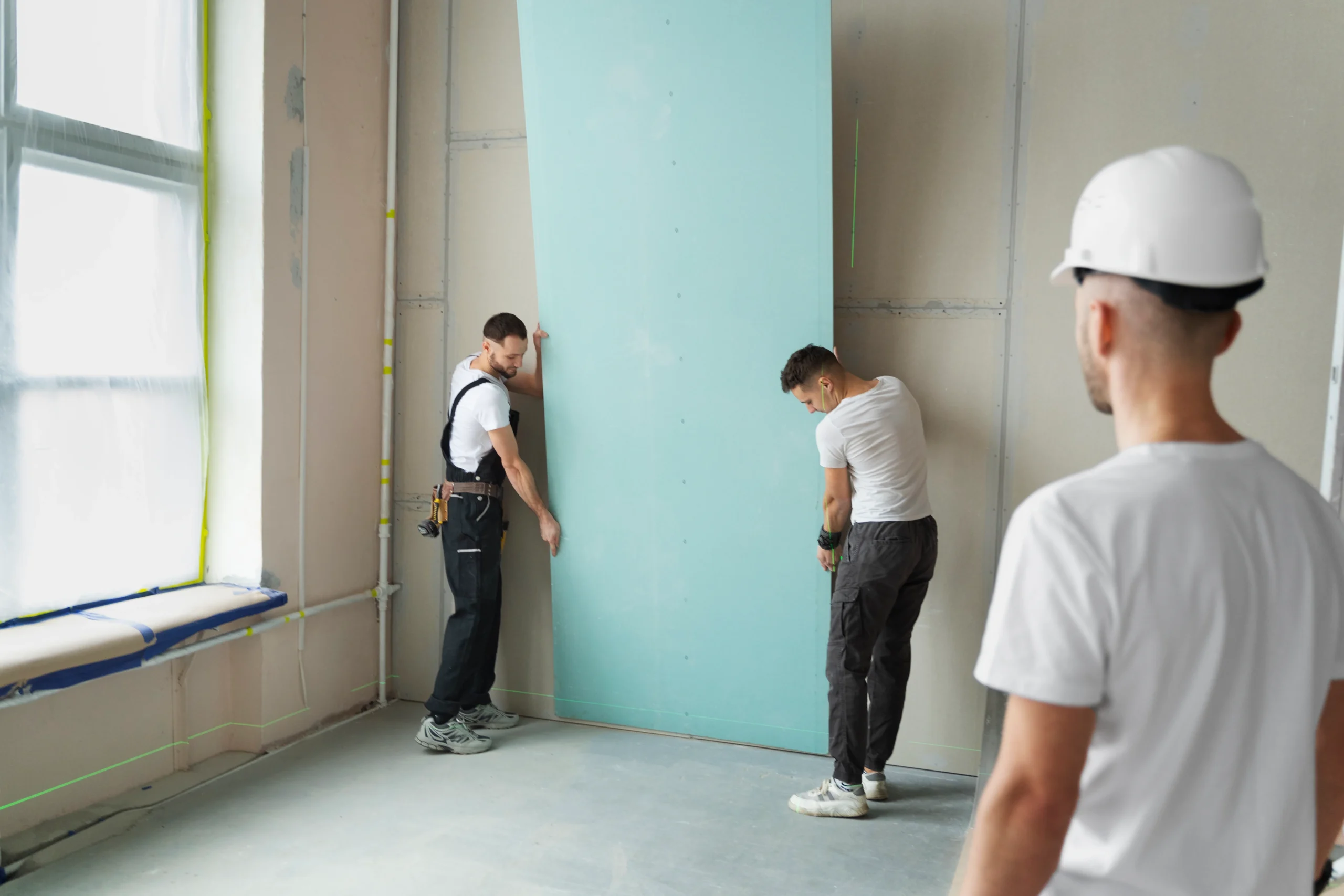 Trabajadores instalando paneles de pladur en un proyecto de construcción.